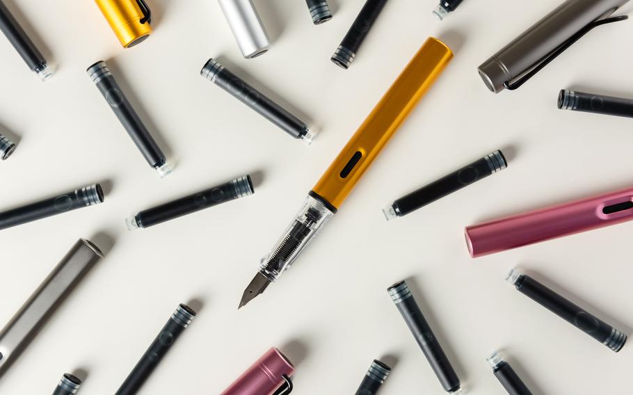 Ink pens and ink cartridges are scattered on the table.