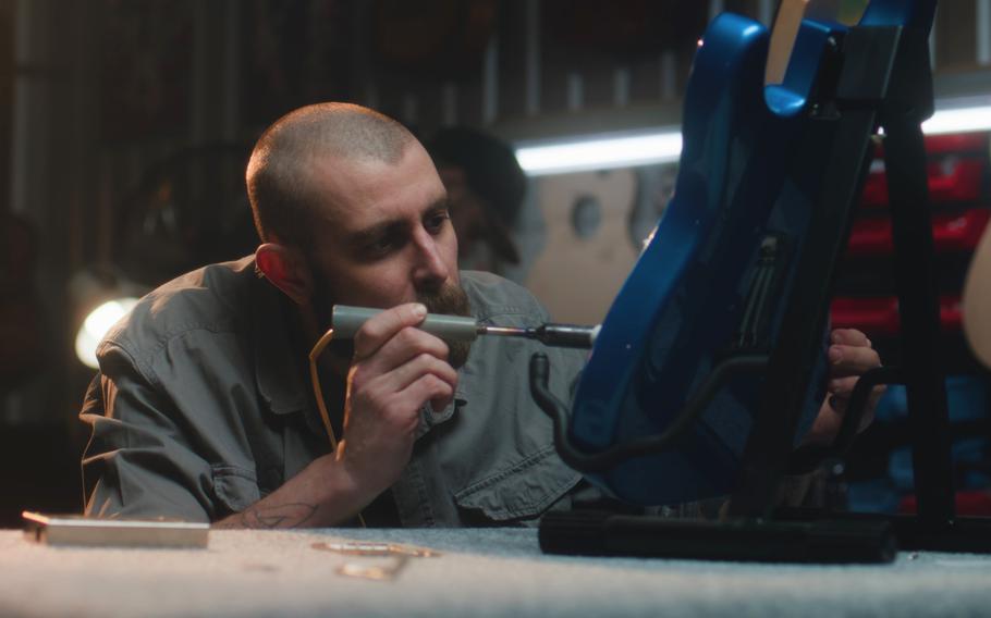 Male carpenter solders guitar strings using soldering iron
