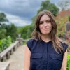 Woman in blue blouse in front of bridge and trees