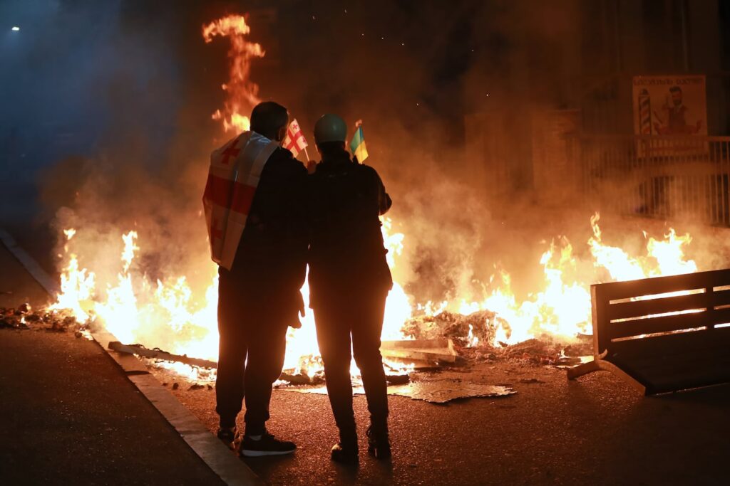 Demonstrators with Georgian and Ukrainian national flags stood behind a burning barricade during an opposition rally in Tbilisi, Georgia, on Oct. 4.