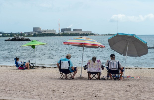 Electric ratepayers have been concerned about the charges related to the Millstone nuclear power station. Here beachgoers enjoy the beach at McCooks Beach in Niantic with Millstone in the background on September 6. (Aaron Flaum/Hartford Courant)