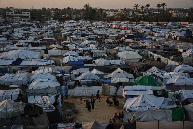 Displaced Palestinians gather outside a tent at a temporary camp in Deir al-Balah, central Gaza Strip, Wednesday, Nov. 26, 2025. (AP Photo/Abdel Kareem Hana)