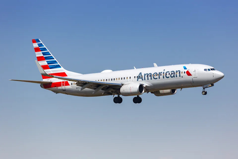 An American Airlines plane flies through a blue sky