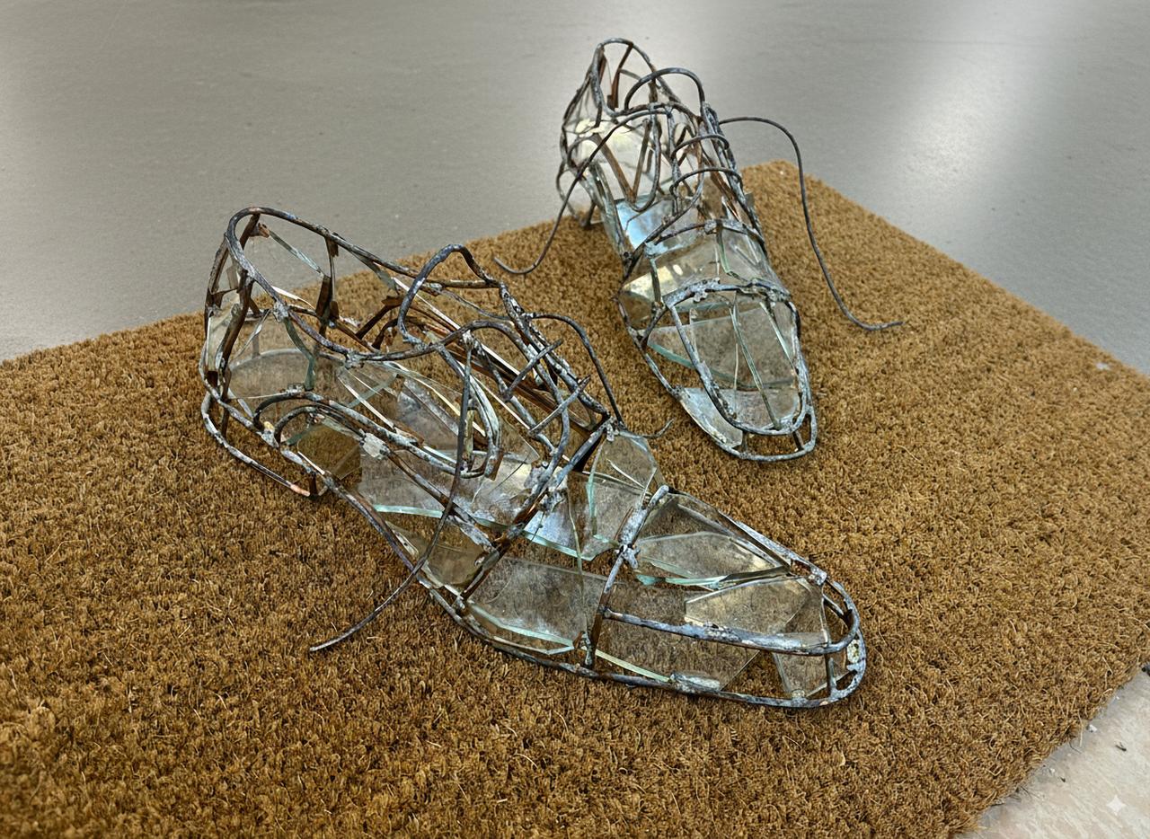 Aysegul Karababa’s “As If Present” displays empty glass shoes at a threshold, recalling her childhood practice of arranging them to make the house feel secure during her father’s absence. (Photo via BASE)