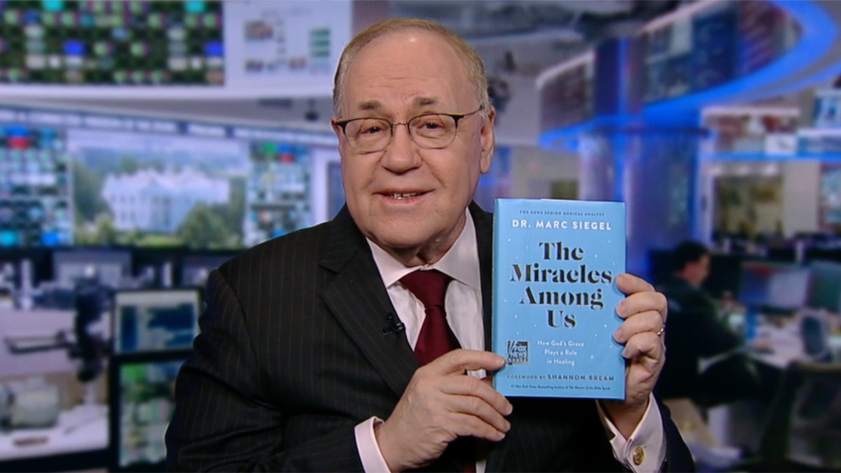 dr. marc siegel holds up his new book