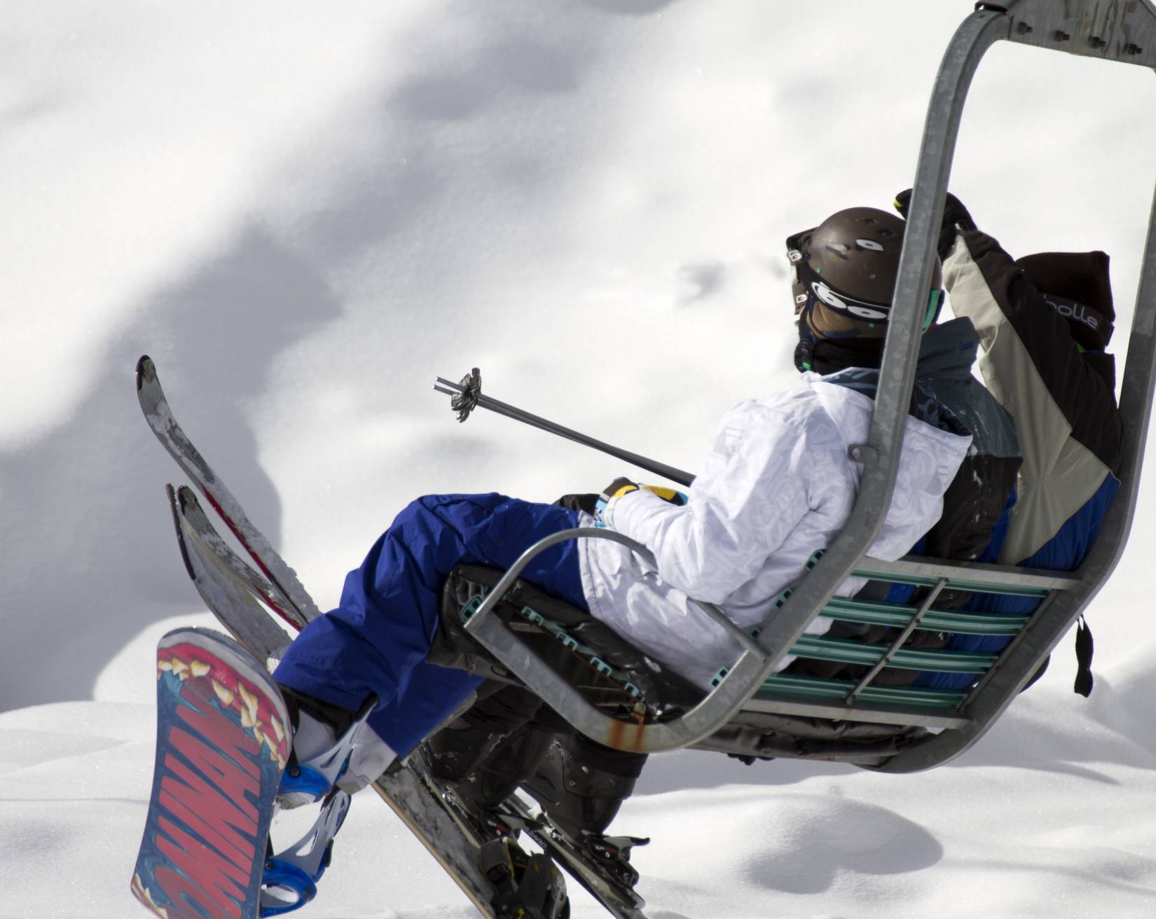 Skiers and snowboarders ride in a winter snow ski hill chair lift at Sunrise Ski Resort near Greer, Arizona 