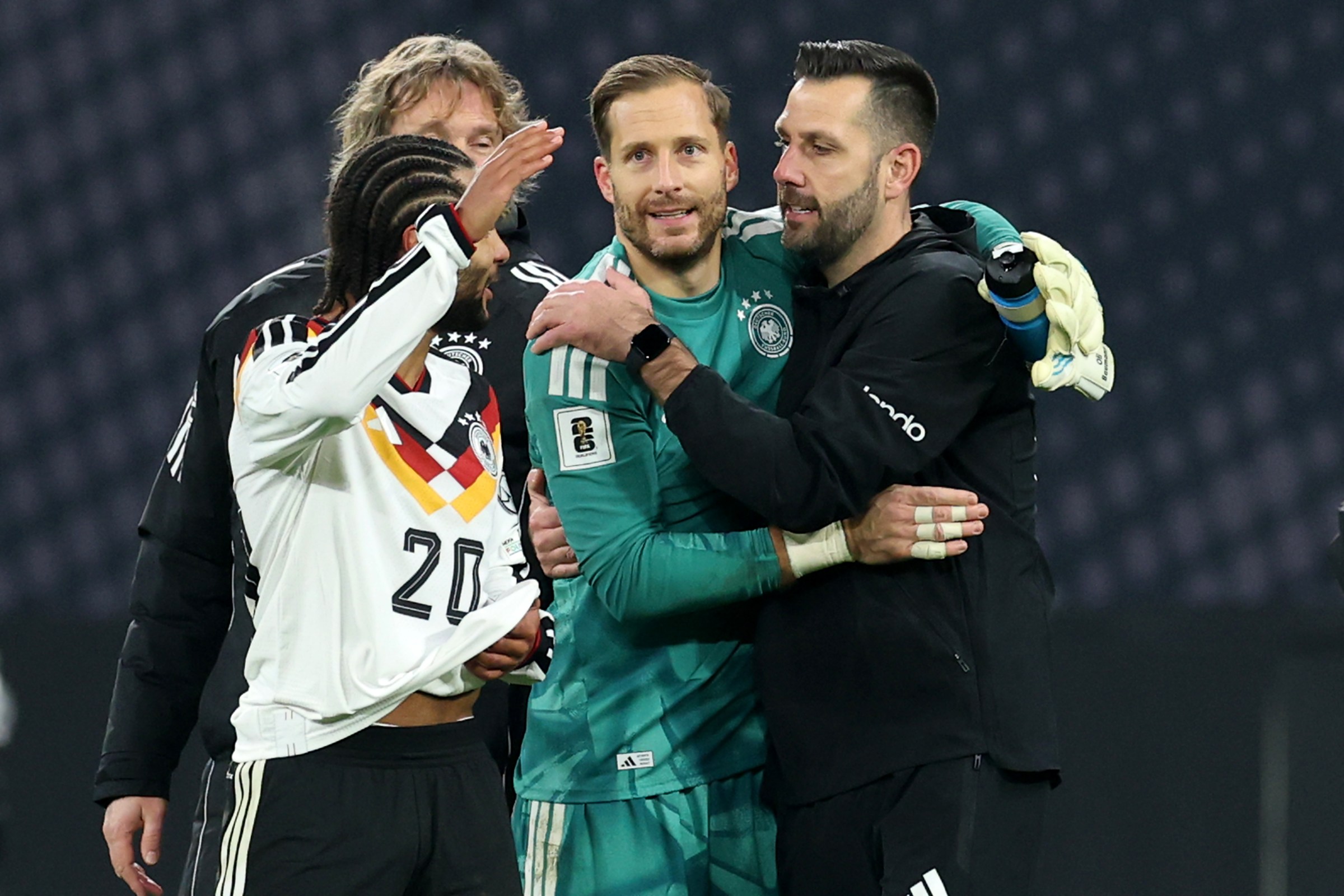 Oliver Baumann shares an embrace with his Germany teammates and assistant coaches after Germany’s win over Slovakia