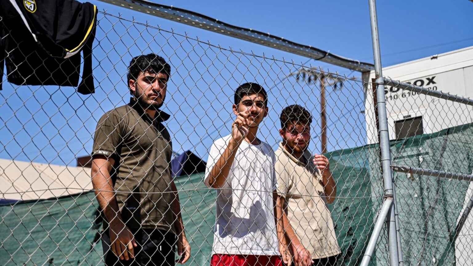 Newly arrived migrants stand in a COVID-19 quarantine area inside the migrant camp on the Greek island of Leros, on September 7, 2021.