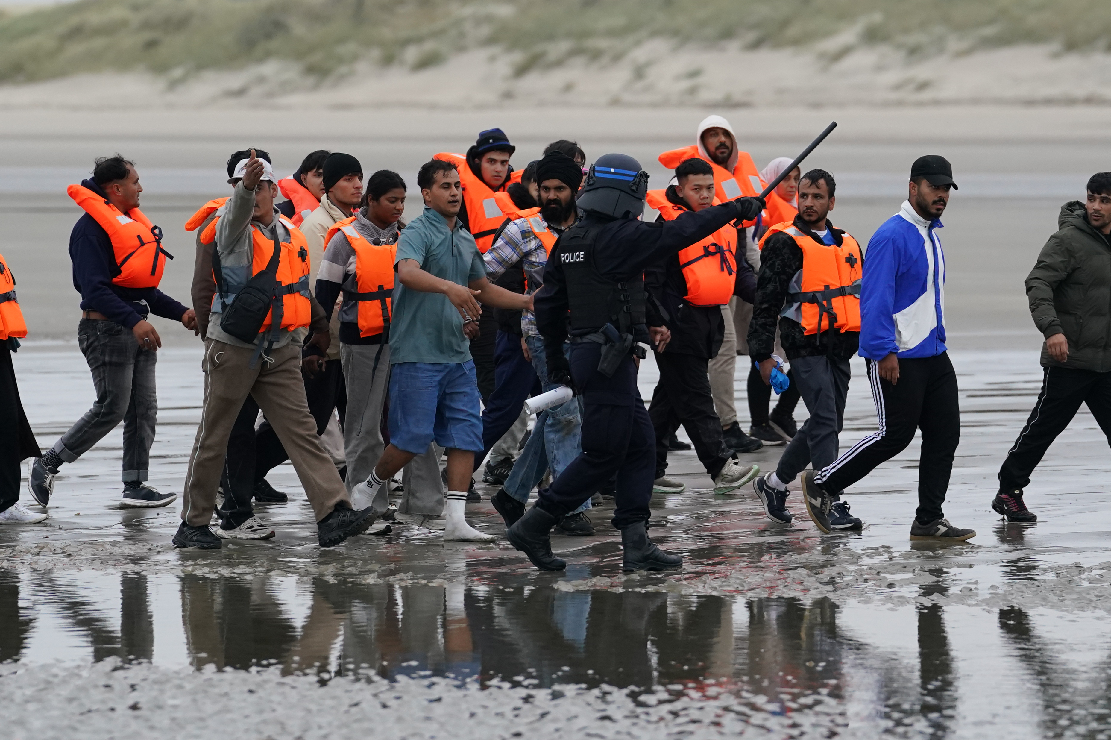 French police officers on a beach in Gravelines, France, talking with people thought to be migrants wearing life jackets.