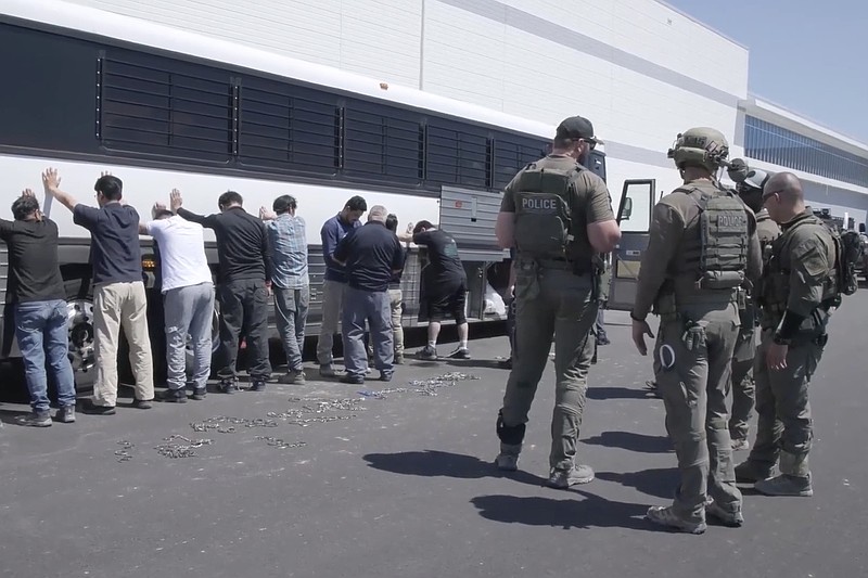 This image from video provided by U.S. Immigration and Customs Enforcement via DVIDS shows manufacturing plant employees waiting to have their legs shackled at the Hyundai Motor Group's electric vehicle plant on Sept. 4, 2025, in Ellabell, Ga. (Corey Bullard/U.S. Immigration and Customs Enforcement via AP, File)