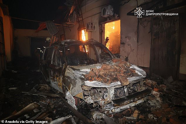 A burned and unusable car is seen as firefighters continue to extinguish the fire that broke out in a house following the Russian drone attacks on Dnipropetrovsk region of Ukraine on December 13, 2025