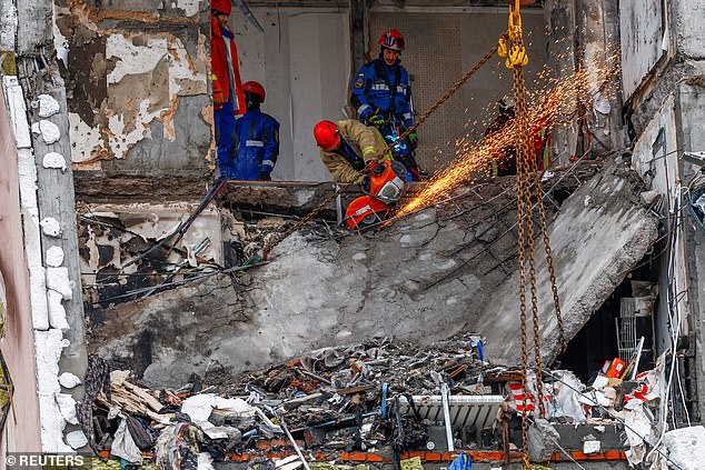 Rescuers work as they search for bodies at the site of an apartment building hit during Russian missile and drone strikes, amid Russia's attack on Ukraine in Kyiv, December 27