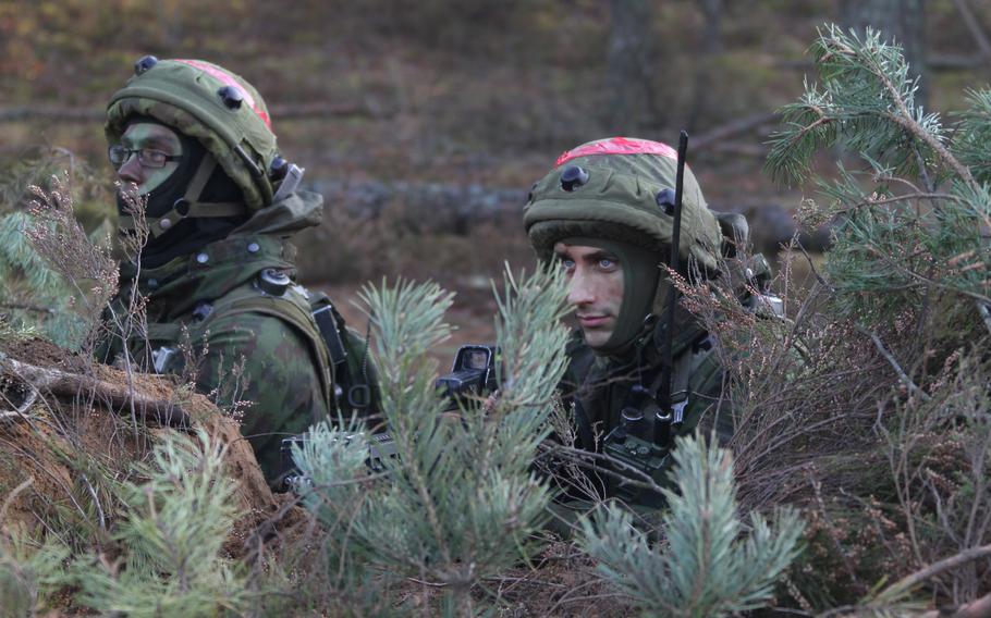 Lithuanian soldiers hide behind plants.