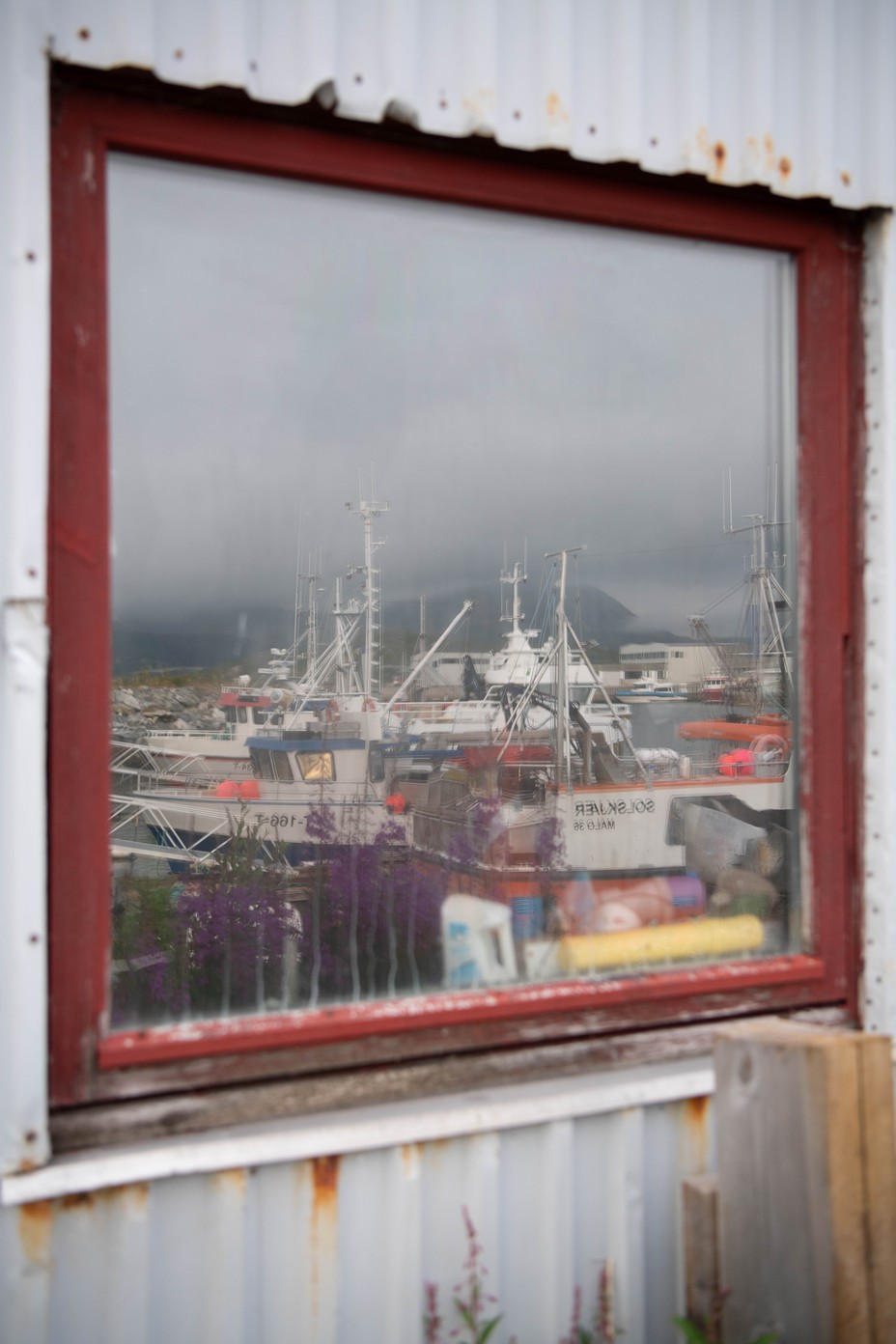 A color photograph of fishing boats reflected in a window of a building