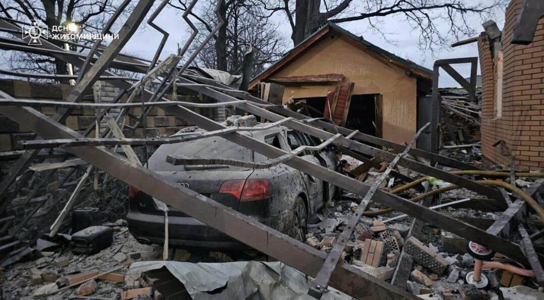 A large fence is seen on top of a car outside a residential home.