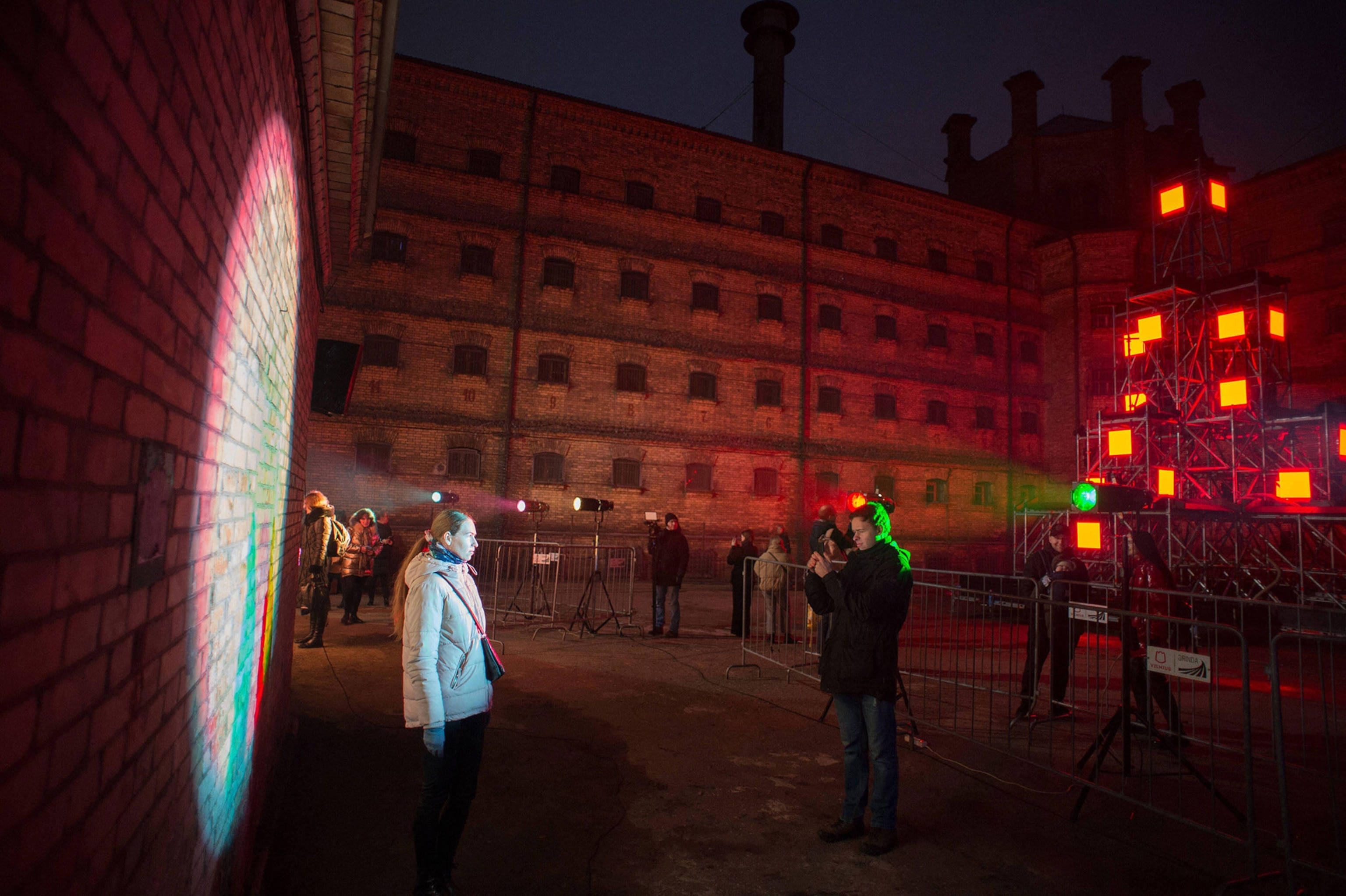 Visitors pose for photos in front of light installations at Alternative Christmas Yard in former Lukiskes Prison.