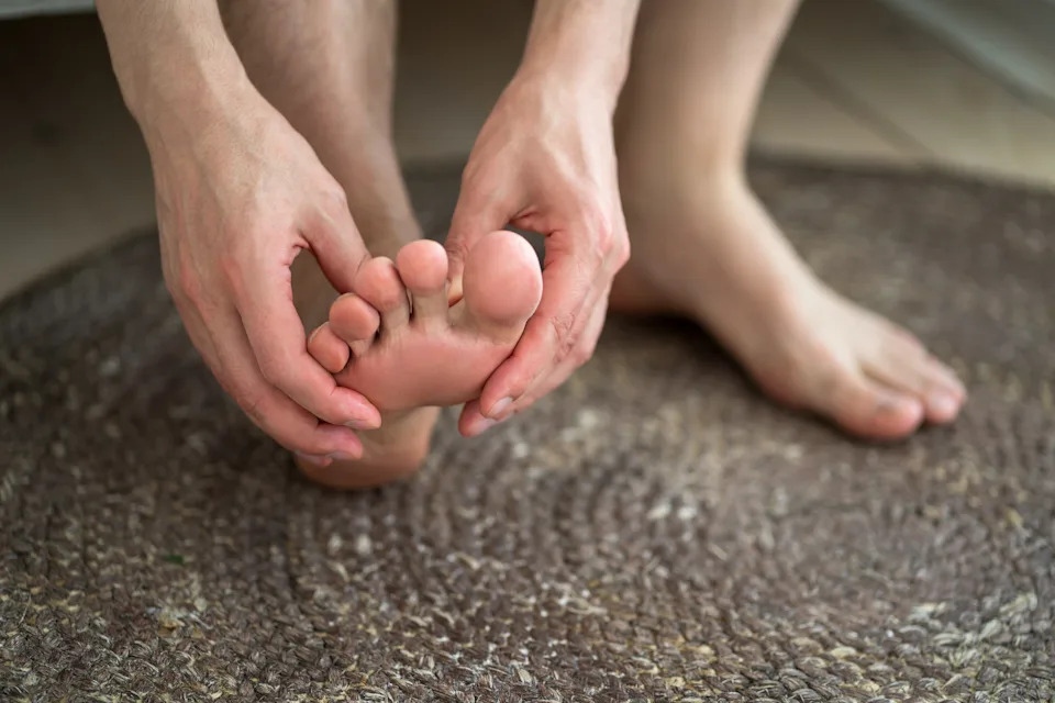 Foot pain, corns and calluses, dry skin on legs, man suffering from feet ache at home, podiatry concept