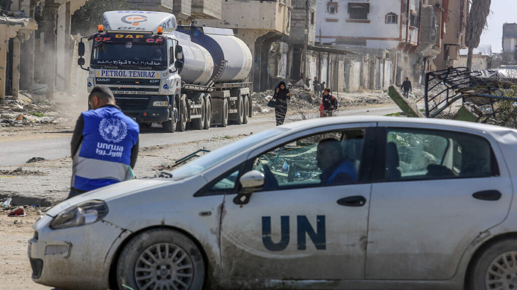 February 17, 2025, Palestinian Territories, Rafah: A UNRWA employee leans against a UN vehicle as trucks carrying humanitarian aid cross the Kerem Shalom border crossing into the Gaza Strip.