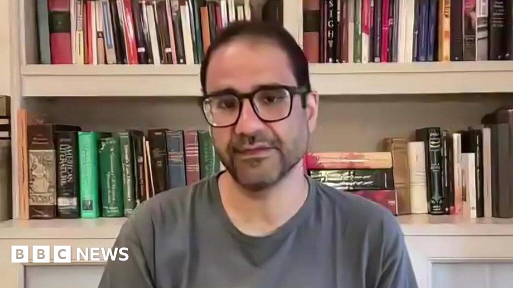 Starmer criticised for welcoming return of Egyptian activist Alaa Abdel Fattah speaks via video link to the BBC in October 2025, sitting in front of a bookshelf and wearing a grey T shirt