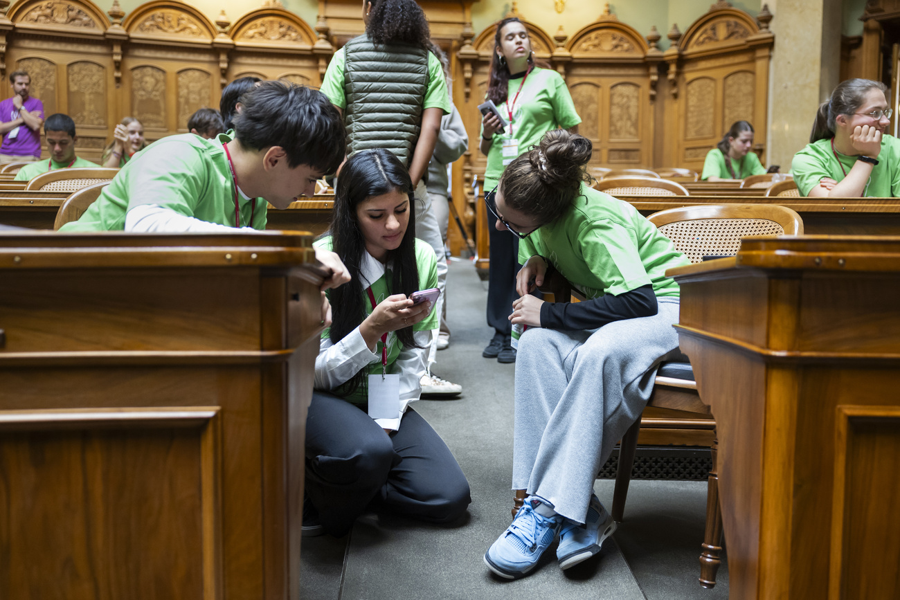 Young people in the National Council chamber looking at a mobile phone.