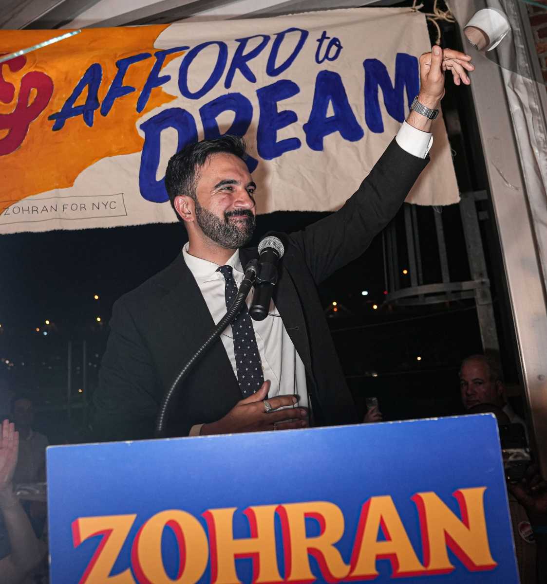 man in suit waving from podium during primary for mayoral election