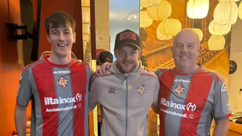 Supplied Two men in a grey and red football shirts either side of Jamie Vardy in a light brown hoodie