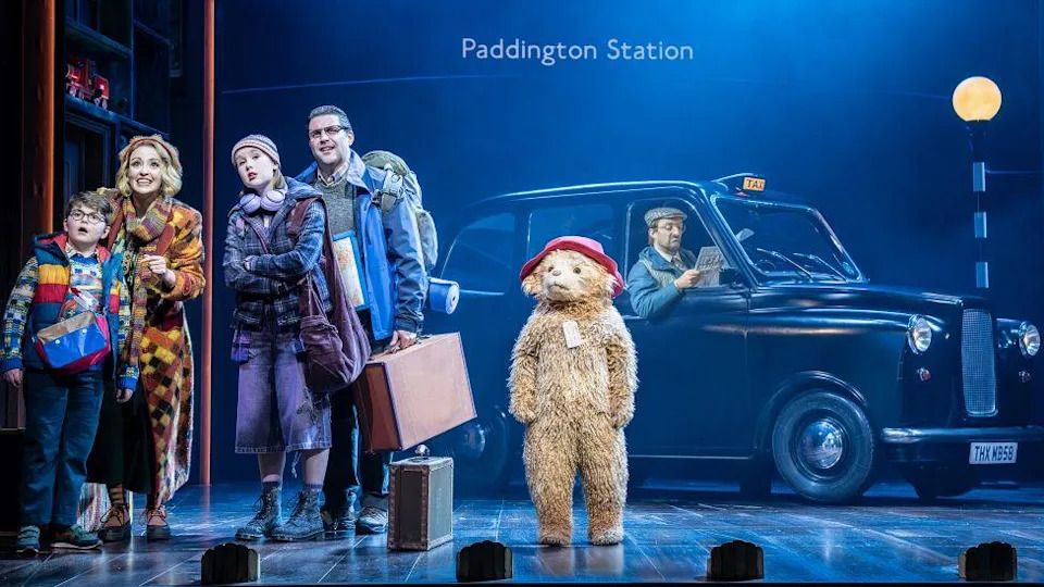 Paddington on stage with the Brown family, with a London black cab in the background