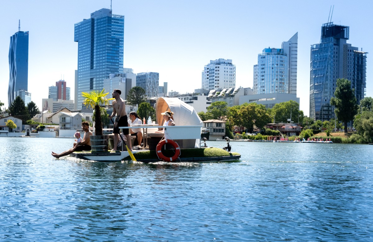 People sail their floating island along the Old Danube river