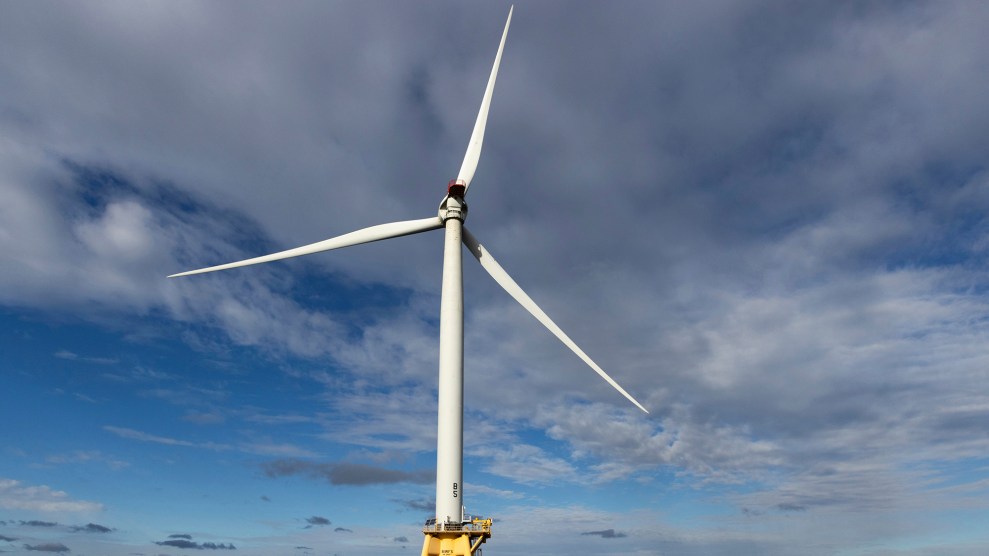 A wind turbine in front of a cloudy sky.