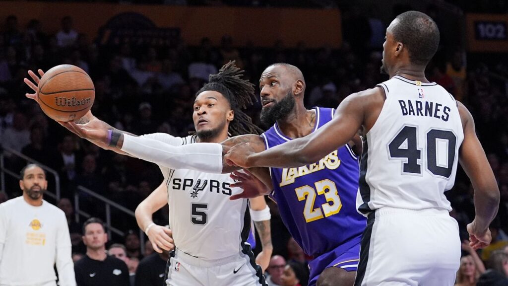 Los Angeles Lakers forward Lebron James (23) goes after a loose ball against San Antonio Spurs forward Harrison Barnes (40) and guard Stephon Castle (5) during the first half of an NBA Cup basketball game Wednesday, Dec. 10, 2025, in Los Angeles. (AP Photo/Jae C. Hong)