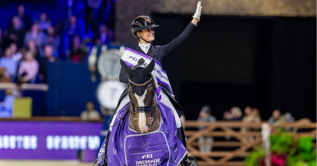 A Dressage World Cup Win for Belgium in Mechelen A woman on a bay dressage horse, smiling and waving to the crowd.
