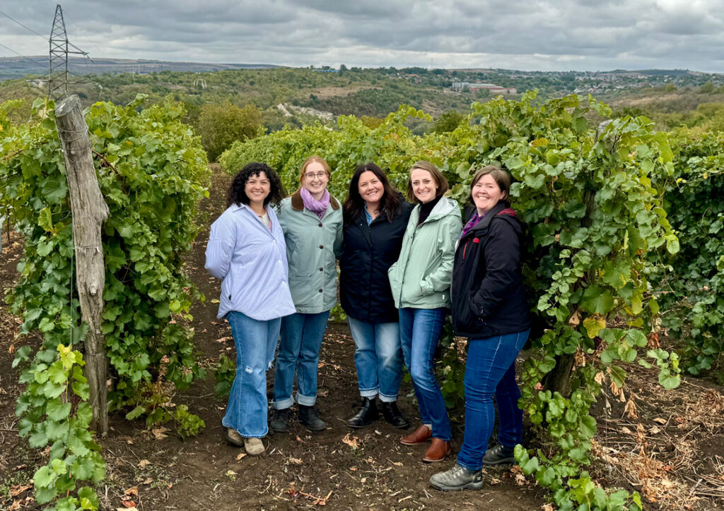 Five women posing for a group photo in a vineyard in Moldova.