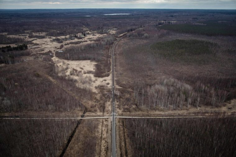 This aerial view shows the Latvian-Russian border and a crossing railway track near Ludza on April 10, 2019. - A Latvian border guard helicopter hovers over a vast forest split by a long, narrow strip of sandy land where a fence topped with barbed wire marks the EU's border with Russia. Fifteen years after Latvia joined both NATO and the European Union, the Baltic state's remote Latgale region -- closer to Moscow than to Brussels -- is among the bloc's poorest areas, but its residents are staunchly pro-European. (Photo by Wojtek RADWANSKI / AFP) (Photo by WOJTEK RADWANSKI/AFP via Getty Images)