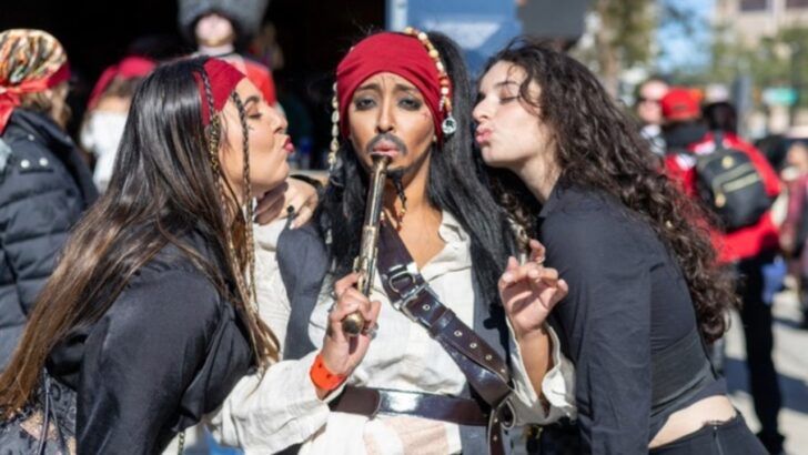 Attendees dressed in pirate costumes gather inside a Tampa bar during a Gasparilla bar crawl event, holding drinks and posing for a photo.
