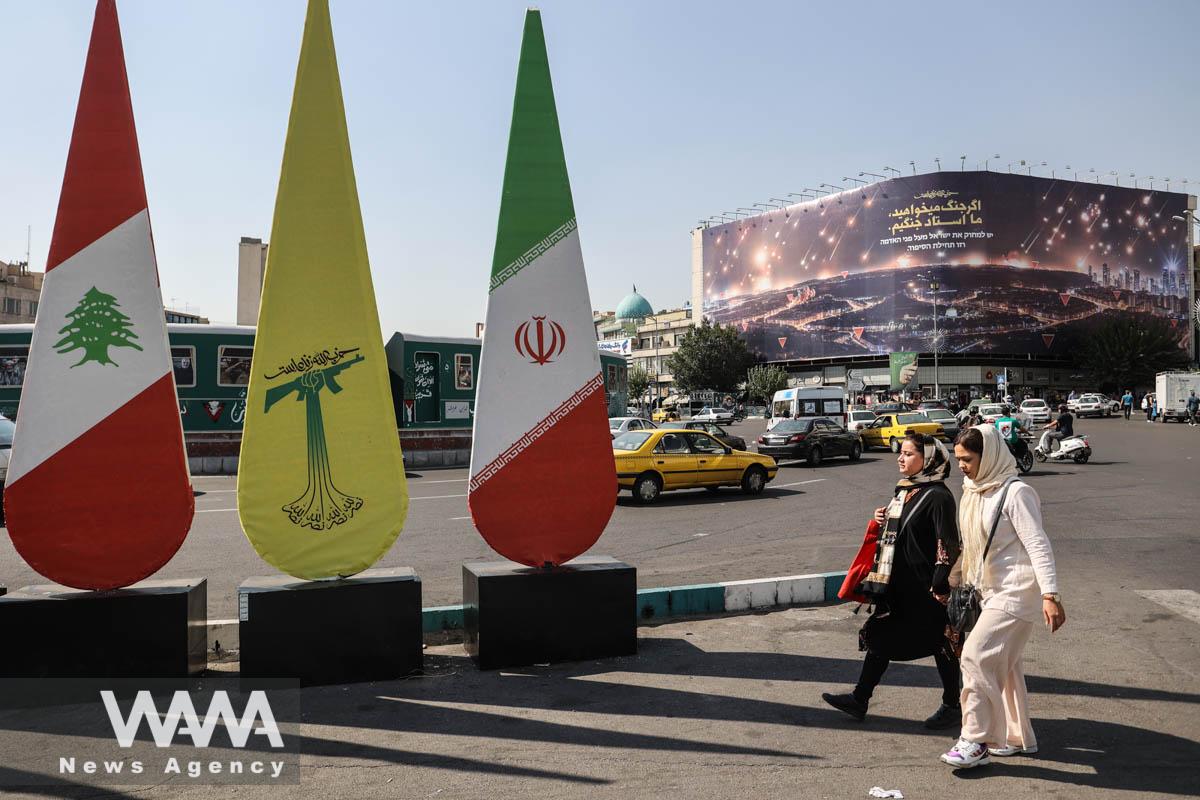People walk past a banner with a picture of the late Lebanon's Hezbollah leader Hassan Nasrallah, in a street