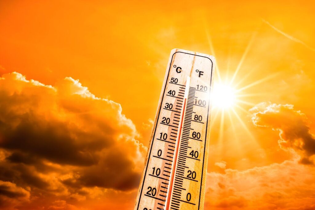 A thermometer stands against an orange sky and glowing sun during a heatwave, illustrating rising temperatures linked to climate change. (Adobe Stock Photo)