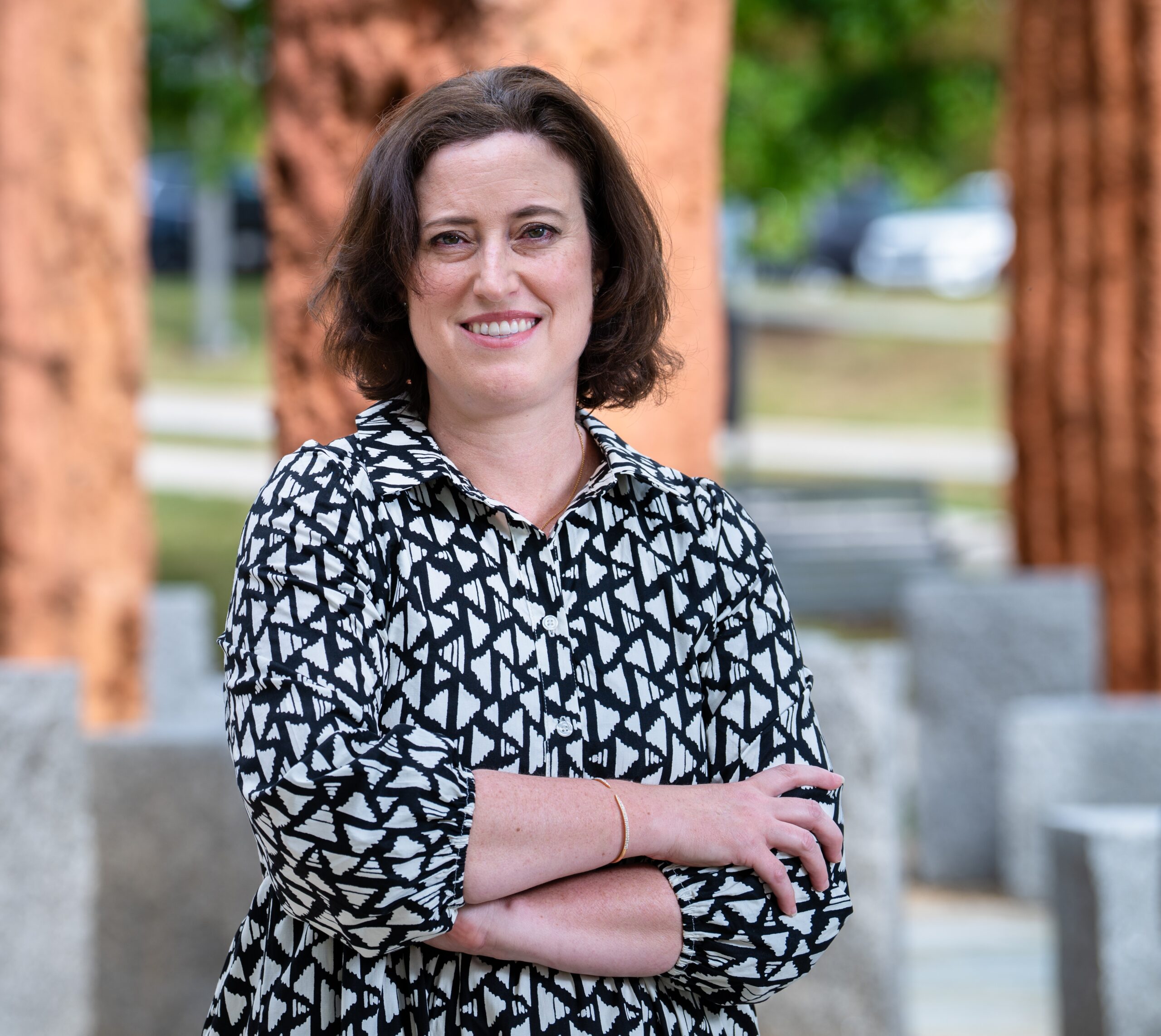 A headshot of, Erin Hogan, a professor wearing a black and white polka-dotted dress. Franco