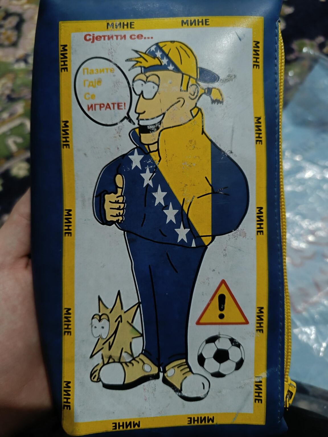 A figure with the symbol of Bosnia and Herzegovina on a pencil case warns children that a mine will blow them up.