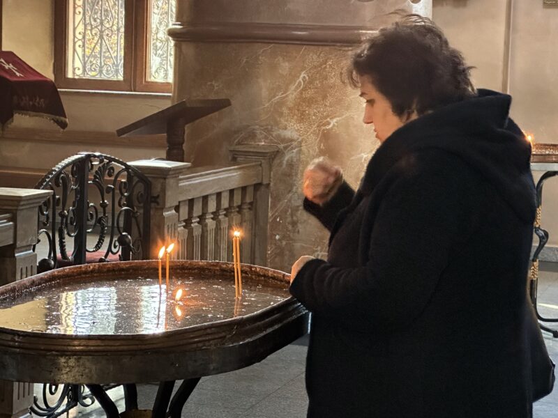 A woman lights candles at the Echmiadzin Church in Tbilisi, Georgia (photo Larry Luxner)