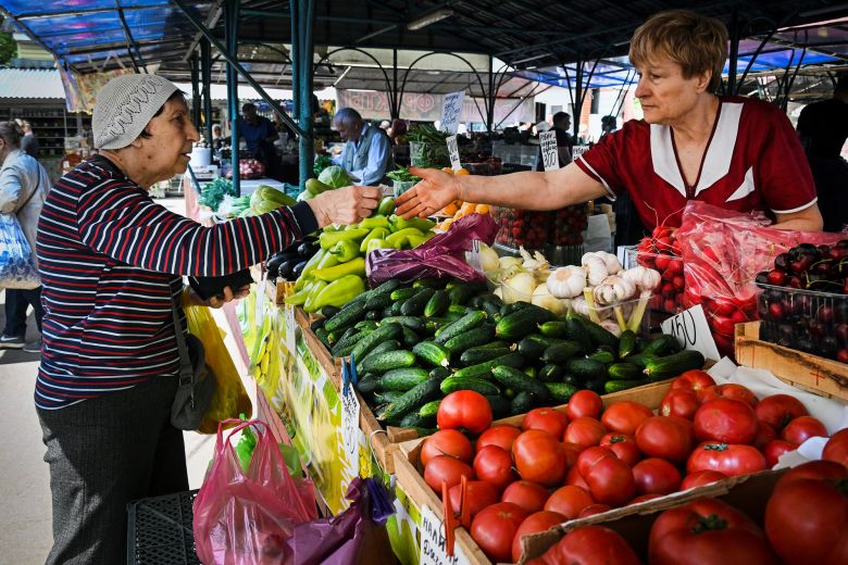 A woman pays for vegetables at a market in Moscow on June 10, 2025. IMF forecasts show that year-over-year inflation in Russia will average 7.6% this year.