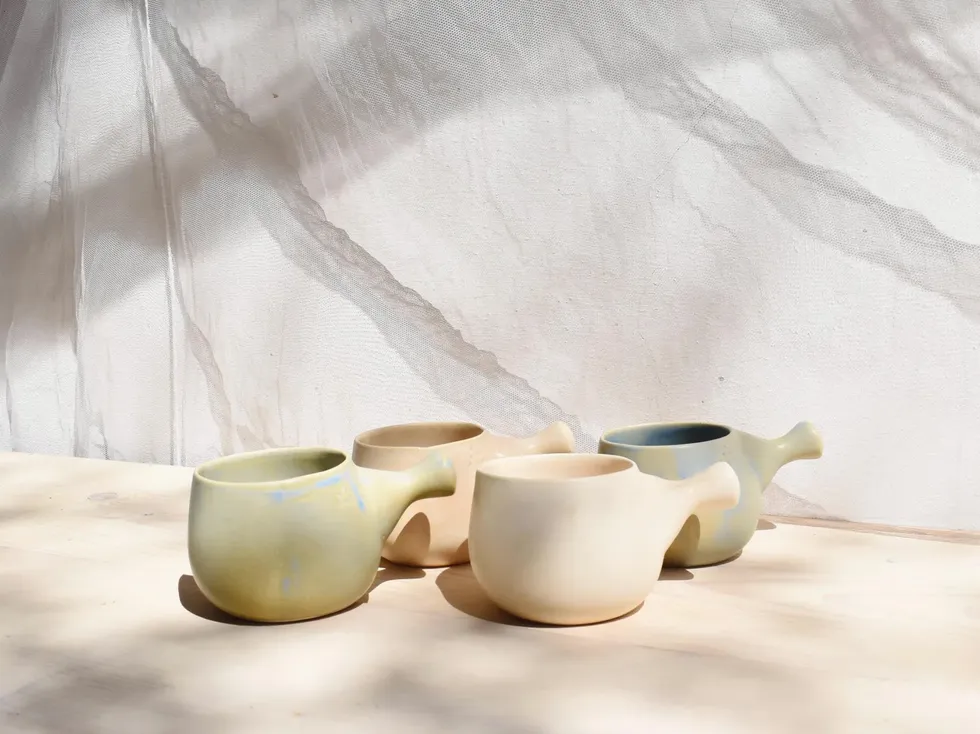 ceramic cups with unique shapes and colors arranged on a wooden surface