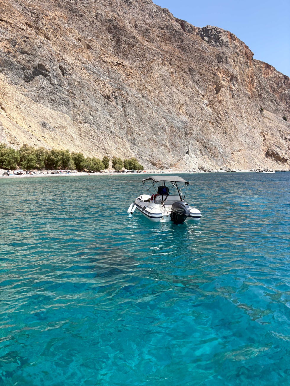 boat anchored in clear turquoise waters near a rocky shore