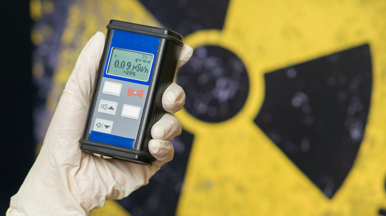 nuclear waste and a hand holding a Geiger counter