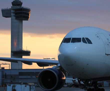 A Delta Air Lines aircraft on the JFK airport apron during sunset.