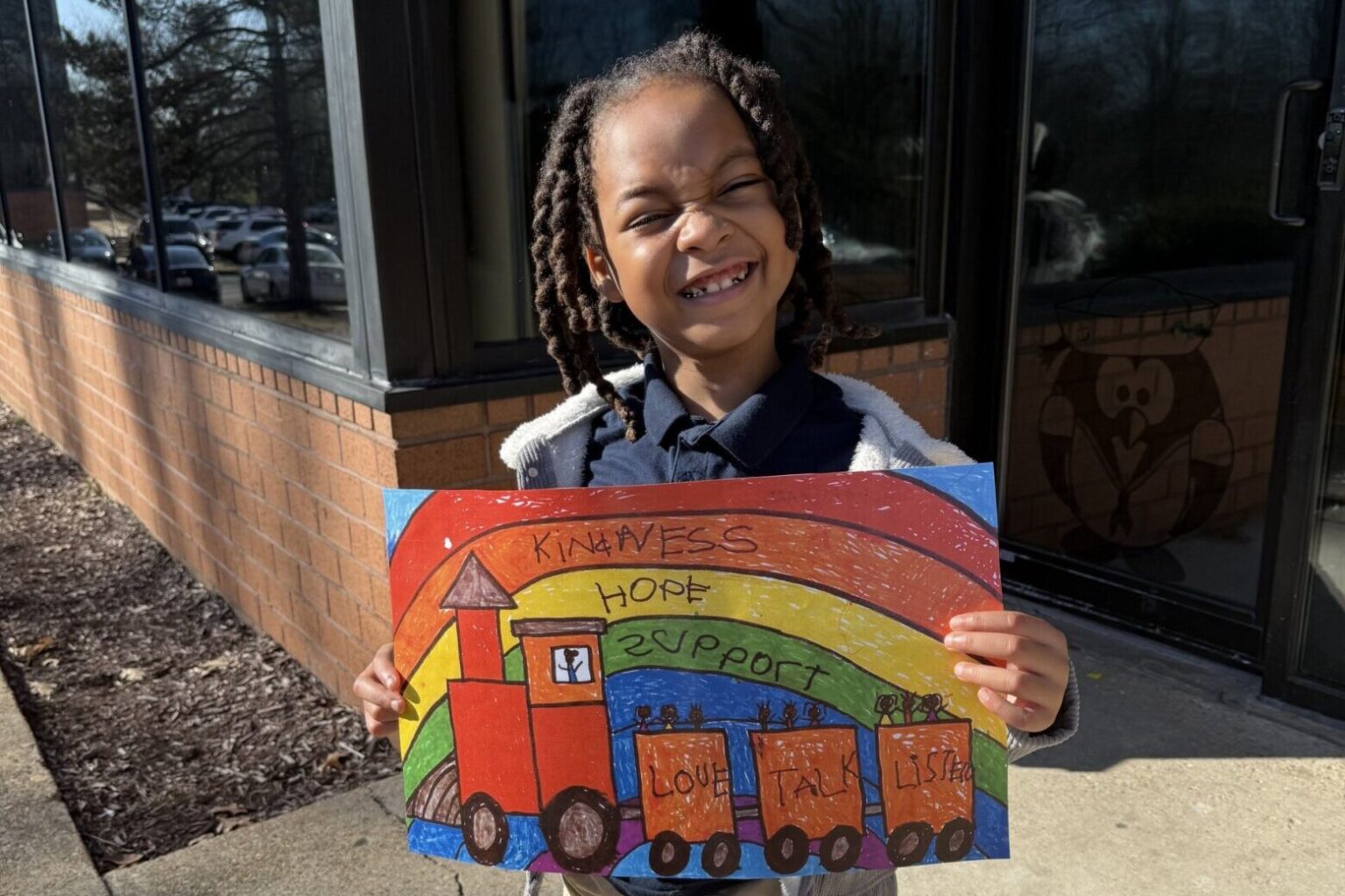 child holding up a poster he drew