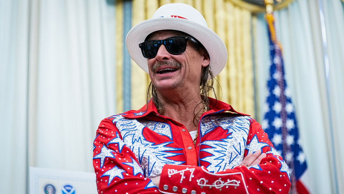 Kid Rock smiles while wearing dark sunglasses and a white hat at the White House.