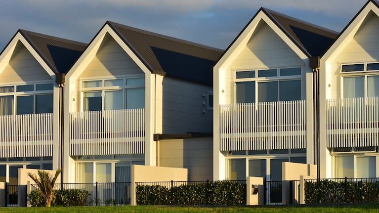 Modern townhouses with gable roofs without overhangs and small yards in front.