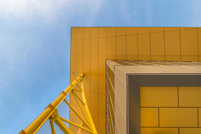 semi-transparent yellow metal arches frame airport’s terminal extension in romania
