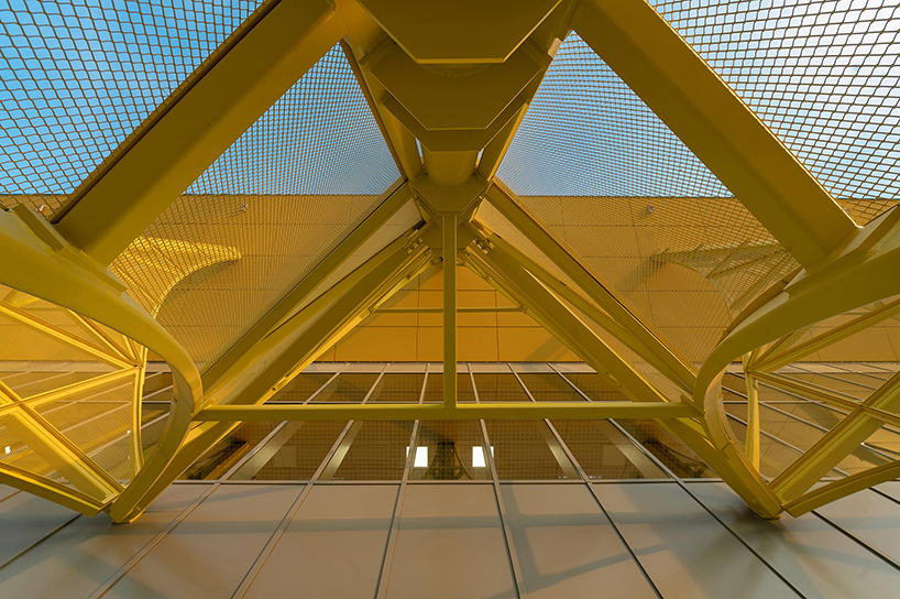 semi-transparent yellow metal arches frame airport’s terminal extension in romania