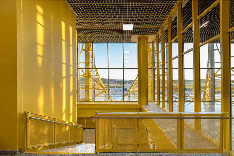 semi-transparent yellow metal arches frame airport’s terminal extension in romania